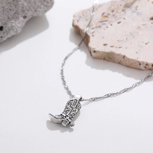 Detail shot of vintage silver cowboy boot pendant with ornate floral engravings