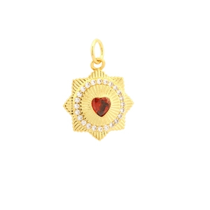 Detailed view of gold sunburst pendant with red heart gemstone and zircon accents