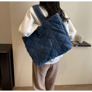 Détail du grand sac cabas en denim bleu matelassé avec bretelles larges et résistantes