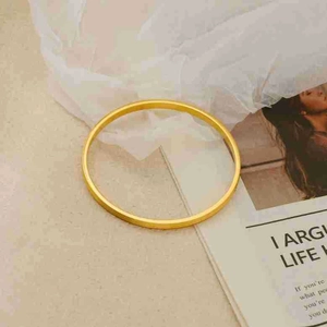 Close-up of minimalist gold-plated titanium steel bracelet with matte brushed texture