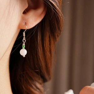 Detail shot of a sea-themed earring with green and white beads on a model