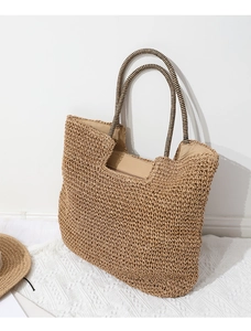 Detailed close-up of woven paper straw texture and striped handle of the beige beach tote
