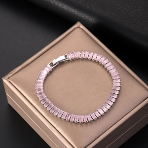 Elegant silver tennis bracelet featuring emerald-cut pink zircon stones on a jewelry box