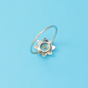 Macro detail of silver stainless steel mustard seed ring with eight-petal flower design