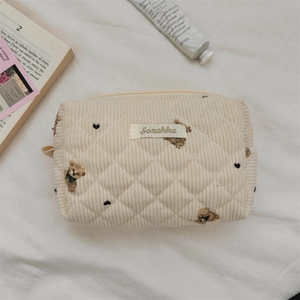 Detail of quilted corduroy pouch with cartoon bear print and minimalist brand label