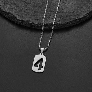 Macro shot of silver stainless steel square box chain and number 4 pendant on rock