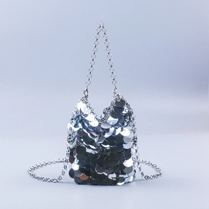 Detail of silver sequin bucket bag featuring metallic discs and polished chain strap