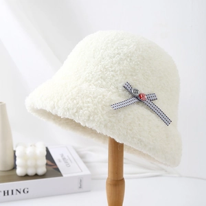 Close-up detail of a white fuzzy bucket hat with a stylish grey bow and button accent