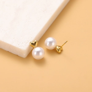 Macro shot of French vintage pearl earrings with gold heart-shaped metal accents