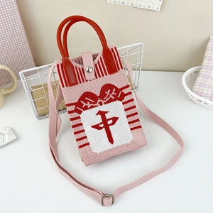Close-up of pink knit crossbody bag with red mahjong character and round handle