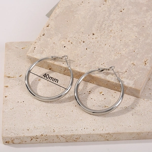Macro detail of 40mm silver circular hoop earrings displayed on textured stone background