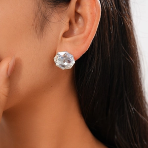 Detailed macro view of geometric faceted glass stud earrings on female model's ear lobe