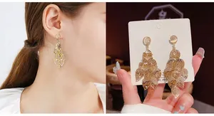 Macro detail of champagne gold layered hollow leaf tassel earrings with cat eye stones