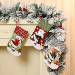Trois grandes chaussettes de Noël avec Père Noël, bonhomme de neige et ours sur la cheminée