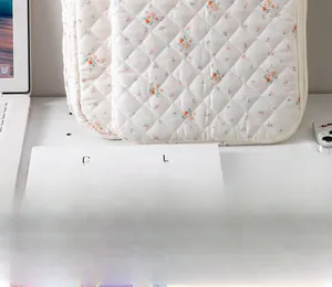 Detailed close-up of quilted floral cotton laptop sleeve with a minimalist desk arrangement