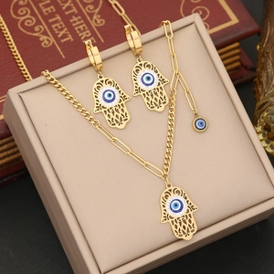 Macro view of gold Hamsa Hand and Evil Eye pendant set on a vintage jewelry display