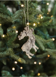 Detail of wooden reindeer ornament with natural bark texture hanging on a Christmas tree