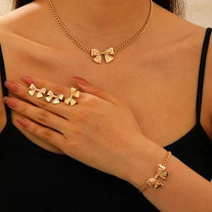 Elegant gold bow jewelry set with necklace bracelet and rings on a model