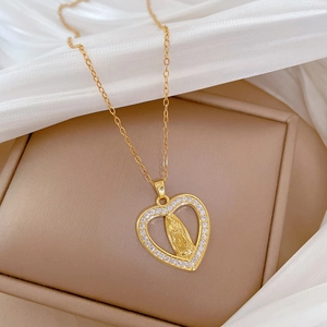 Detail of gold heart pendant with Virgin Mary relief and crystal inlay on silk