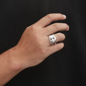 Macro detail of men's silver chain-style titanium steel ring on a textured black background