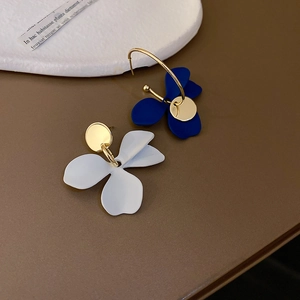 Détail de boucles d'oreilles asymétriques avec pétales bleu foncé et blancs sur or