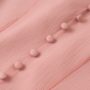 Detail view of pink crepe fabric with matching fabric-covered buttons and fine stitching