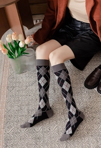 Detail of argyle knee-high socks with red accents and vintage college style aesthetic