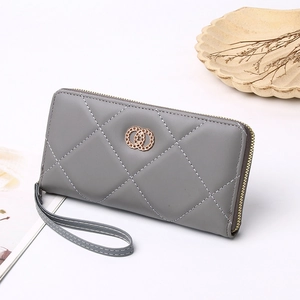 Detail of grey quilted long wallet with gold zipper and shell decorative background