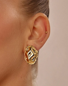 Detailed view of irregular gold molten earrings with star motif on a female model