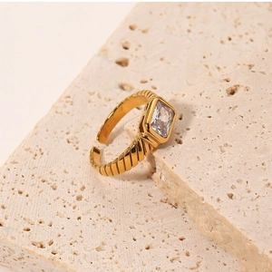 Close-up of 18k gold plated stainless steel ring with square zircon on travertine stone