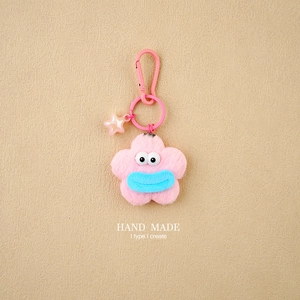 Detail of pink plush flower keychain with blue mouth and colorful star charm