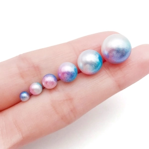 Detail of colorful gradient mermaid pearls in various sizes displayed on a finger