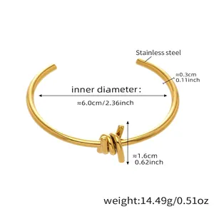Detalle de brazalete abierto de acero inoxidable dorado con diseño de nudo trenzado
