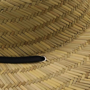 Macro detail of natural straw sun hat texture with black cord and silver eyelet