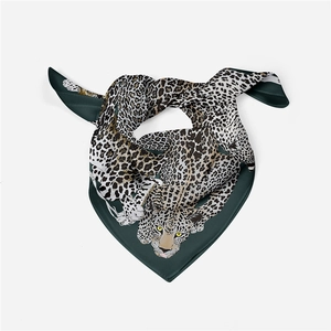 Detailed close-up of dark green silk scarf featuring leopard print and smooth texture