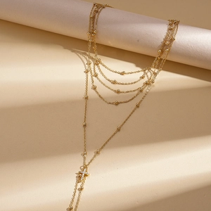 Close-up of golden multi-layer chain necklace with zircon cross pendant and metal beads