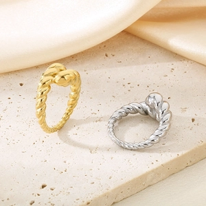 Close-up of twisted 18K gold and silver plated stainless steel rings on a silk base