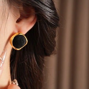 Gros plan d'une boucle d'oreille floquée noire avec bord doré portée par un modèle
