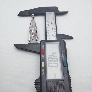 Digital caliper measuring a 48mm silver metal pendant with ornate hollow design detail