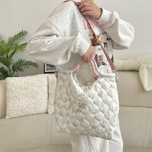 Vue détaillée du sac cabas matelassé blanc avec motifs floraux et anses roses