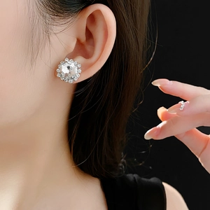 Macro shot of silver stud earring with large round crystal and pavé halo on model