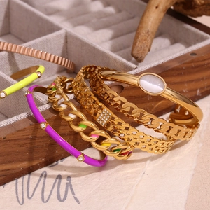 Detail view of 18K gold plated chain bracelets and enamel bangles in a jewelry box