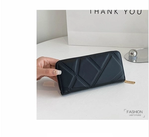 Detail of black PU leather wallet with geometric quilting and gold zipper closure
