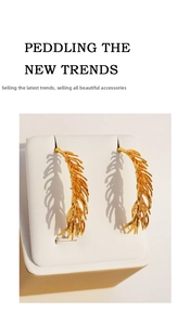Detailed macro view of vintage gold feather earrings with intricate leaf texture
