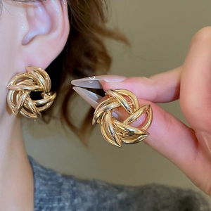Close-up of golden woven swirl earrings with a vintage metallic texture for women