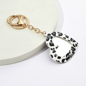 Leopard print heart-shaped mirror keychain with golden metal hook on a white background
