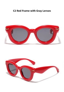 Detail view of red cat eye sunglasses with gray lenses and gold accents on frame