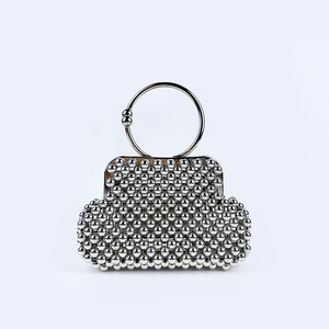 Close-up of a silver beaded evening bag with a metallic ring handle and modern shell shape