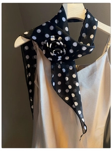 Close-up of vintage black and white polka dot chiffon scarf with an elegant flower detail