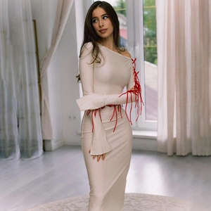 Detailed view of cream off-shoulder dress featuring red lace-up tassels on long sleeves